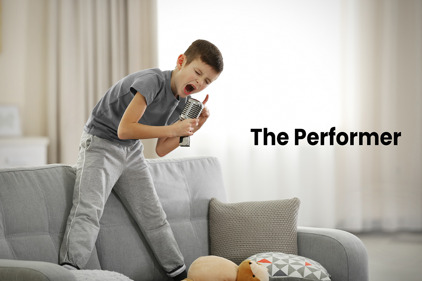Little boy singing with microphone on a sofa at home the performer